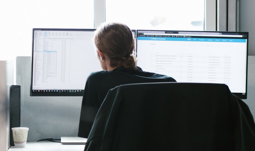 Woman working on two computers monitors